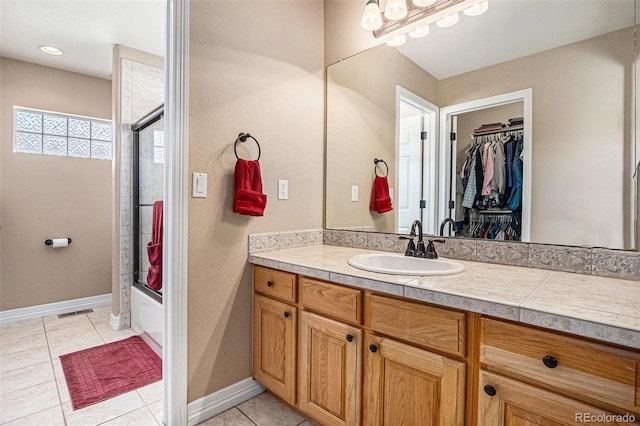11065 W Rockland Dr, Littleton, CO 80127 - bathroom with vanity, tile patterned floors, enclosed tub / shower combo, a walk in closet, and baseboards