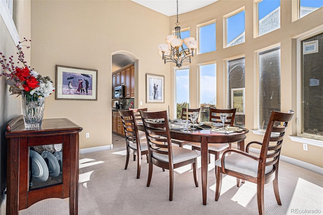 11065 W Rockland Dr, Littleton, CO 80127 - dining space with light carpet, a chandelier, arched walkways, baseboards, and a high ceiling