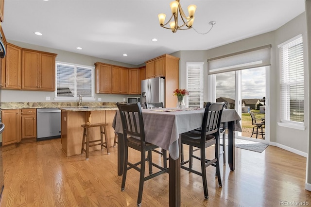 kitchen featuring a breakfast bar, light wood finished floors, a chandelier, stainless steel appliances, and recessed lighting