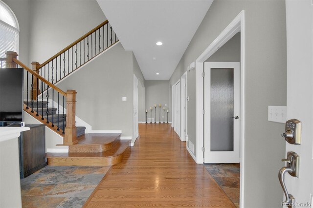 hallway with stairs, recessed lighting, and wood finished floors