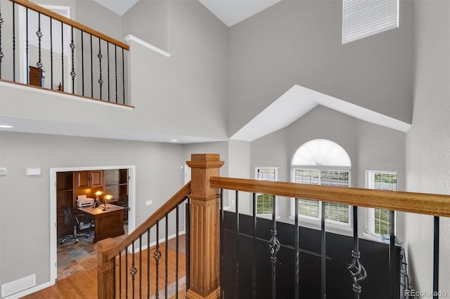 stairway with visible vents, baseboards, and a towering ceiling