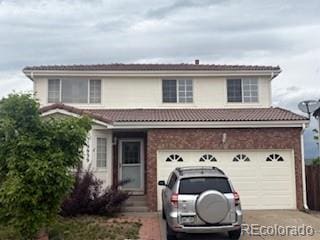 19939 Mitchell Cir, Denver, CO 80249 - traditional-style home featuring a tile roof, driveway, brick siding, and an attached garage