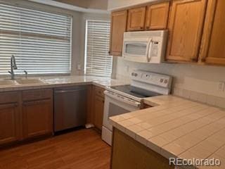 19939 Mitchell Cir, Denver, CO 80249 - kitchen with white appliances, wood finished floors, and brown cabinets