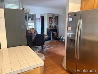 19939 Mitchell Cir, Denver, CO 80249 - kitchen featuring stainless steel fridge, tile countertops, wood finished floors, and arched walkways