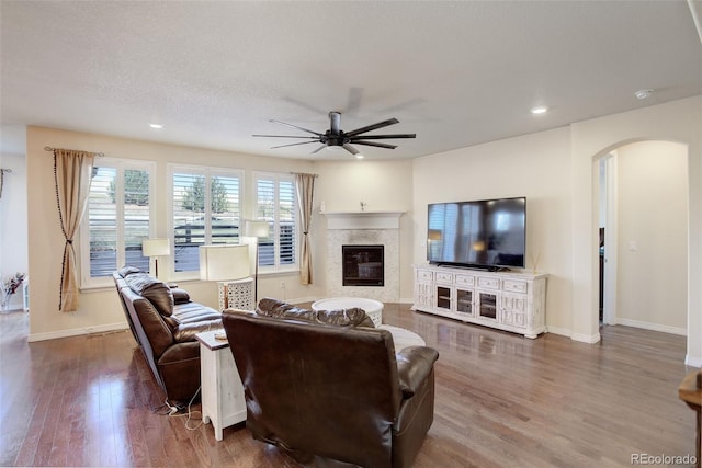 living room with ceiling fan, wood-type flooring, and a textured ceiling