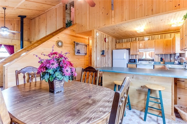 62 Rubel Cir, Westcliffe, CO 81252 - dining room with wooden ceiling, wooden walls, a ceiling fan, and a wood stove
