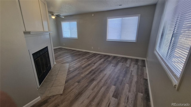 unfurnished living room featuring ceiling fan, a textured ceiling, and dark hardwood / wood-style flooring