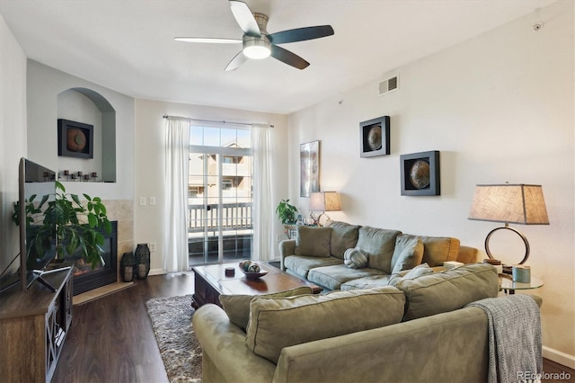 living room featuring ceiling fan, dark hardwood / wood-style flooring, and a tile fireplace