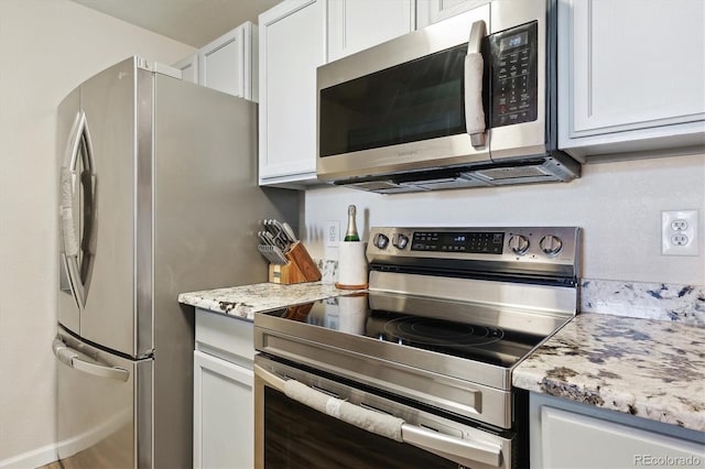 kitchen featuring light stone countertops, stainless steel appliances, and white cabinetry