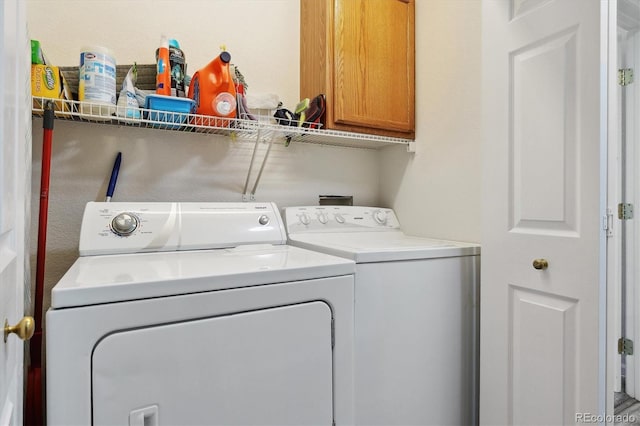 clothes washing area with cabinets and washer and clothes dryer