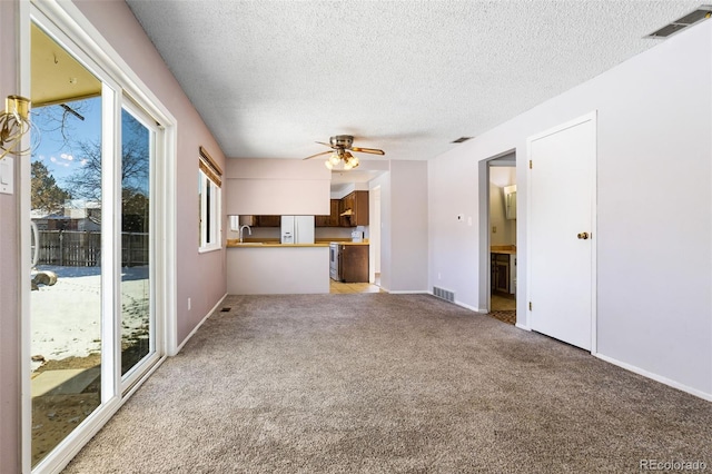 unfurnished living room featuring light carpet, sink, a textured ceiling, and ceiling fan