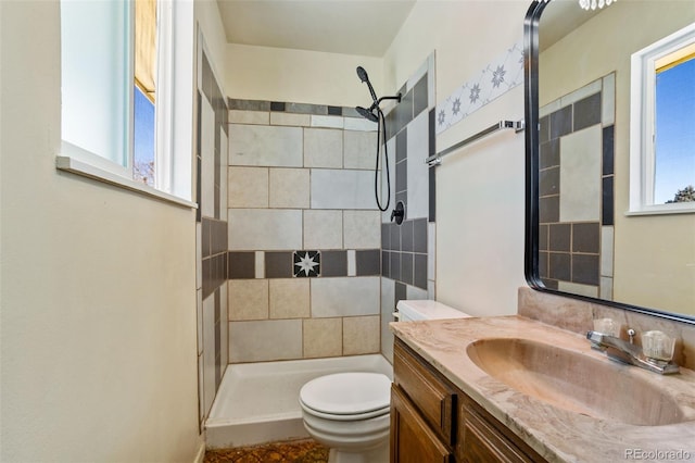 bathroom with vanity, toilet, and a tile shower