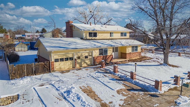 snow covered rear of property featuring a garage