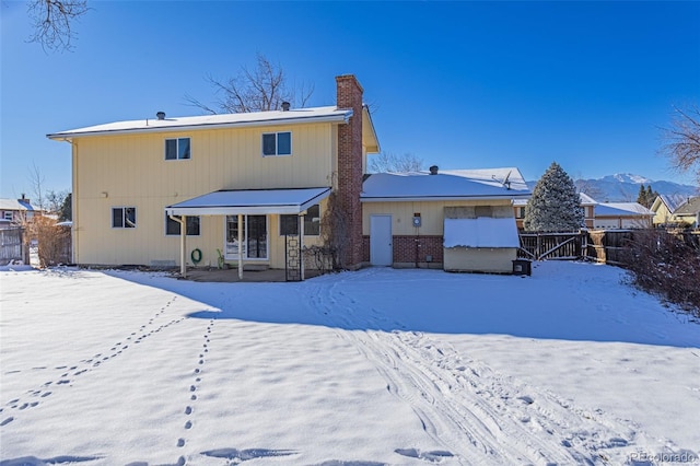 snow covered rear of property featuring a mountain view