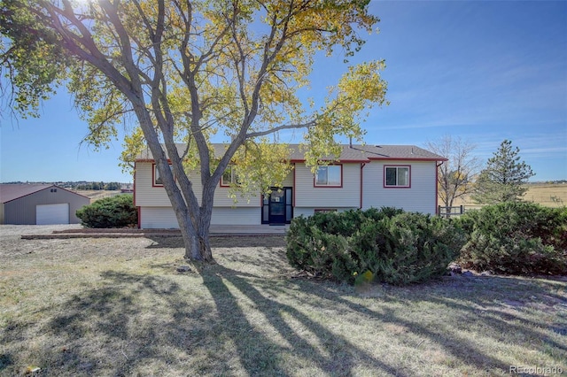 view of front of property featuring an outbuilding, a front lawn, and a garage