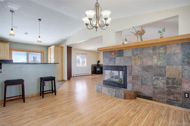 living room with baseboard heating, light hardwood / wood-style flooring, a fireplace, and plenty of natural light