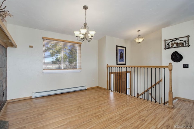 spare room featuring light hardwood / wood-style flooring, baseboard heating, and a chandelier