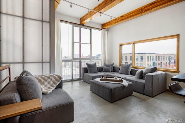 living area with concrete flooring, beamed ceiling, rail lighting, and a city view