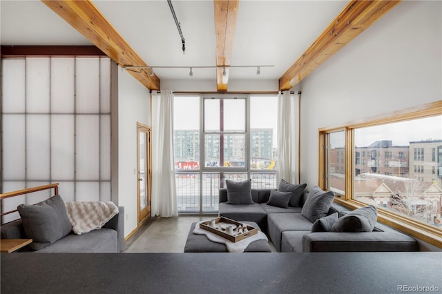 living area featuring a view of city, concrete floors, beam ceiling, and track lighting