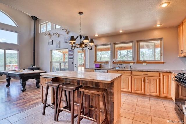 kitchen featuring gas stove, an inviting chandelier, a kitchen island, pendant lighting, and light tile patterned floors