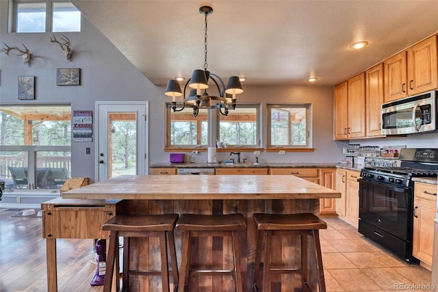 kitchen featuring light brown cabinets, black range with gas cooktop, wooden counters, and an inviting chandelier