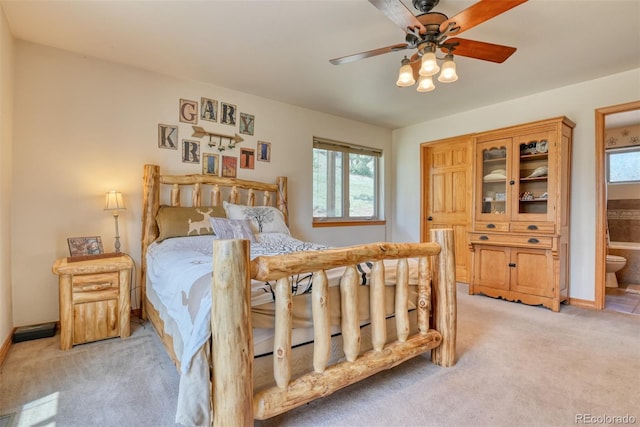 bedroom with ensuite bathroom, ceiling fan, and light colored carpet