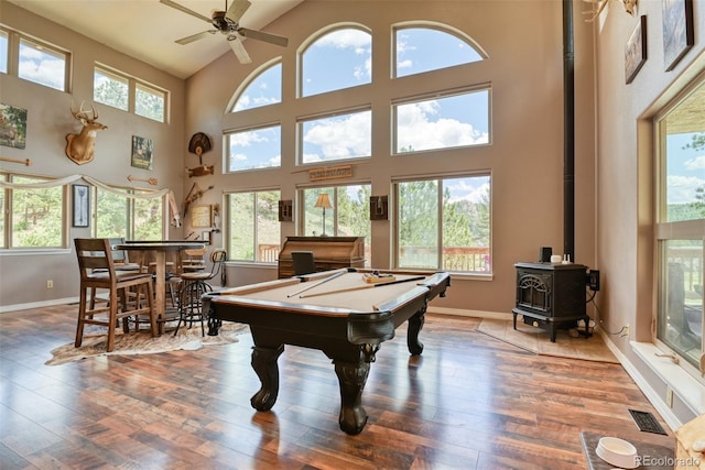 playroom with a wood stove, high vaulted ceiling, billiards, bar area, and wood-type flooring