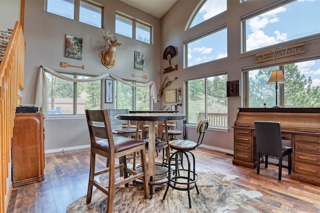 dining area featuring a towering ceiling and wood-type flooring