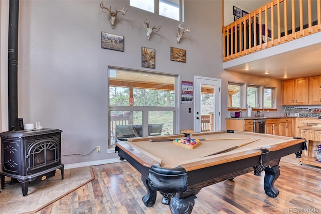 rec room featuring a towering ceiling, a wood stove, a wealth of natural light, and pool table