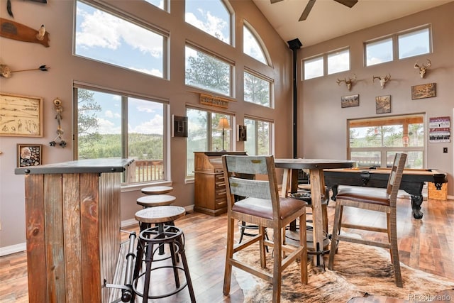 dining space featuring ceiling fan, light hardwood / wood-style flooring, a high ceiling, and pool table