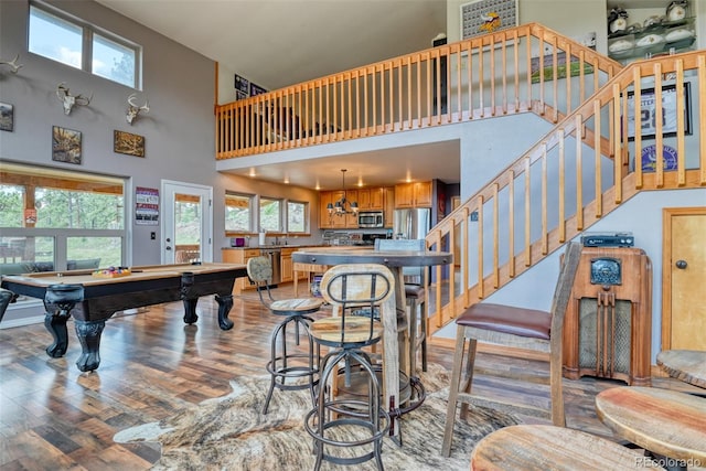 rec room with light hardwood / wood-style floors, a high ceiling, and pool table