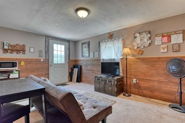 living room with a textured ceiling, carpet floors, and wooden walls