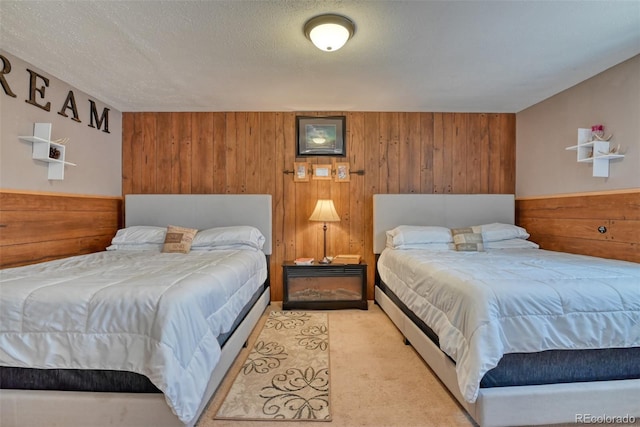 bedroom with wood walls, light colored carpet, and a textured ceiling