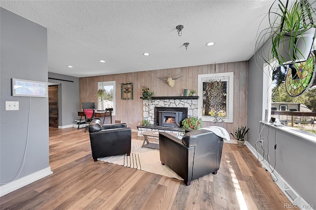 living room featuring light hardwood / wood-style floors, a textured ceiling, and wooden walls