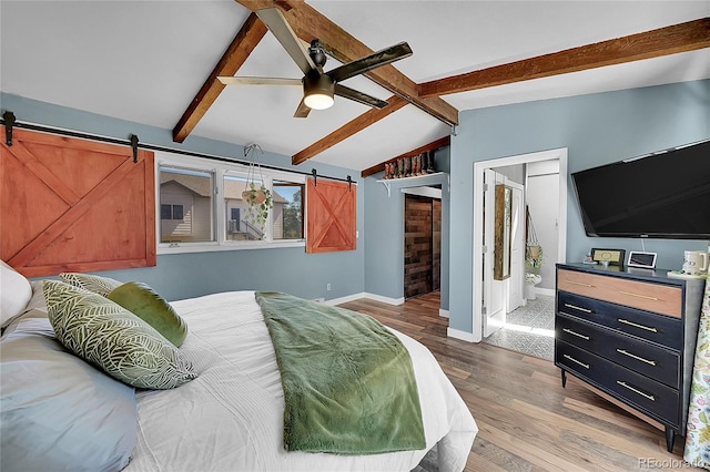 bedroom with connected bathroom, hardwood / wood-style floors, a barn door, and ceiling fan