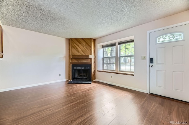 4130 E 94th Ave Unit B, Thornton, CO 80229 - unfurnished living room featuring a large fireplace, a textured ceiling, and wood finished floors
