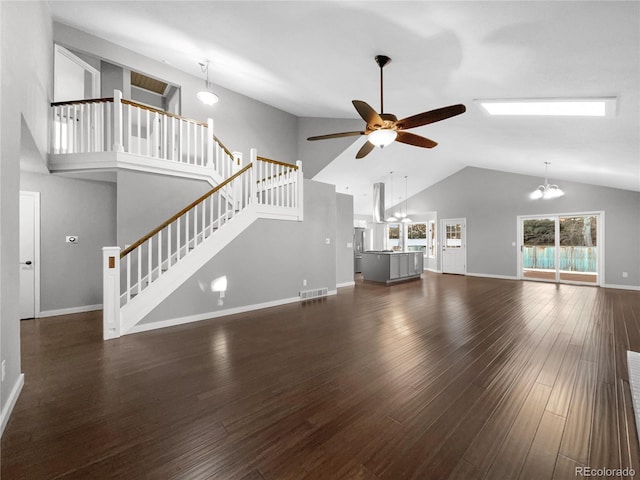 unfurnished living room featuring dark wood-type flooring, high vaulted ceiling, and ceiling fan with notable chandelier