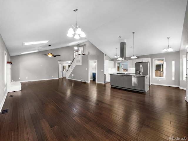 unfurnished living room featuring dark hardwood / wood-style flooring, ceiling fan with notable chandelier, and high vaulted ceiling