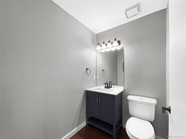 bathroom featuring vanity, hardwood / wood-style flooring, vaulted ceiling, and toilet