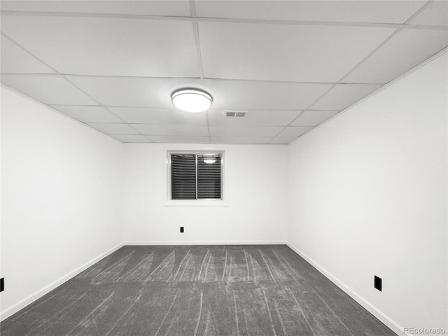 spare room with dark colored carpet and a paneled ceiling