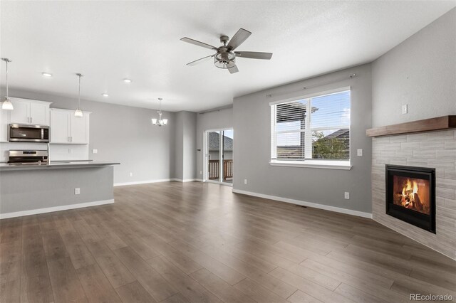 2248 Rosette Ln, Castle Rock, CO 80104 - unfurnished living room featuring a glass covered fireplace, ceiling fan, a chandelier, dark wood-style flooring, and recessed lighting