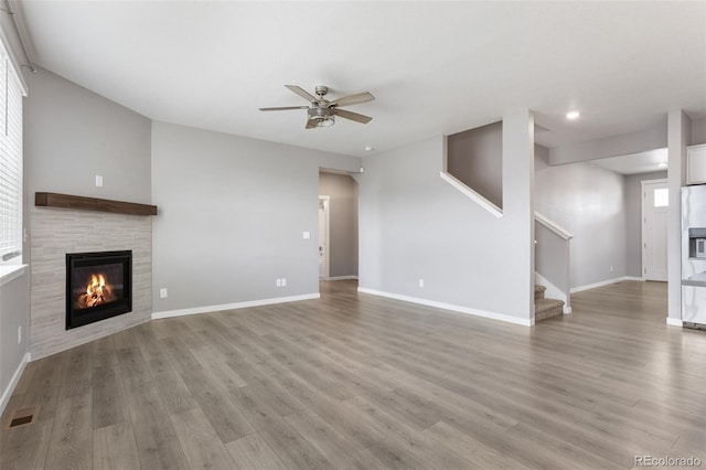 2248 Rosette Ln, Castle Rock, CO 80104 - unfurnished living room with a tile fireplace, a ceiling fan, wood finished floors, stairway, and recessed lighting