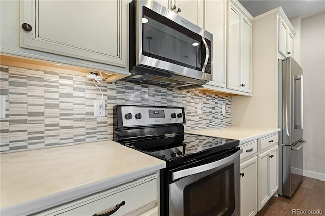 kitchen featuring dark wood-style floors, stainless steel appliances, white cabinets, light countertops, and decorative backsplash