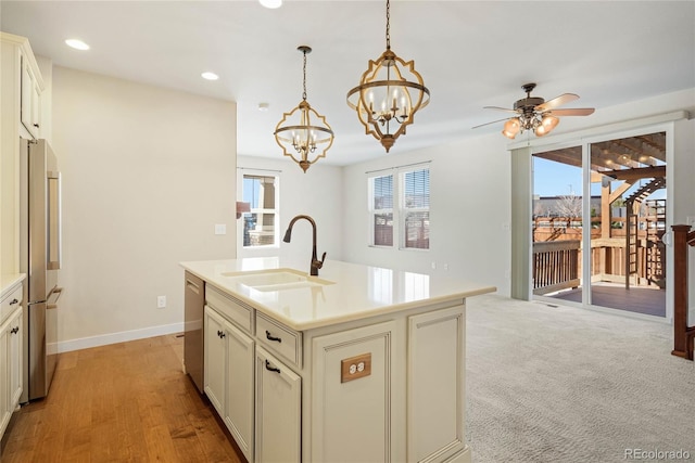 kitchen with pendant lighting, a kitchen island with sink, ceiling fan with notable chandelier, sink, and stainless steel appliances