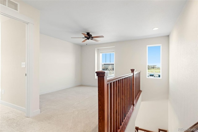 corridor with visible vents, an upstairs landing, carpet, and baseboards