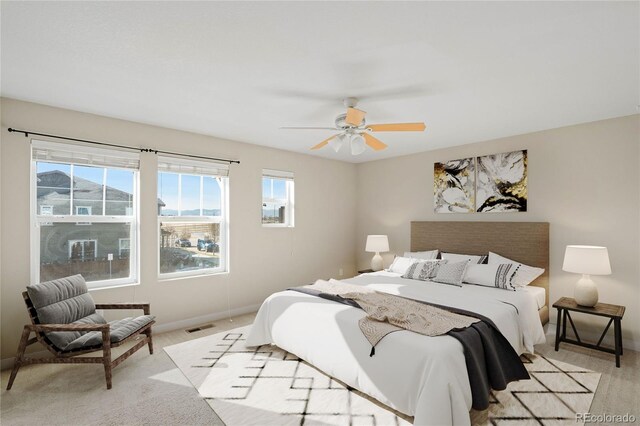 bedroom with light carpet, visible vents, ceiling fan, and baseboards