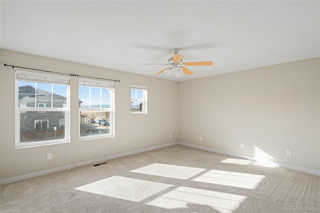 unfurnished room with visible vents, baseboards, light colored carpet, and ceiling fan