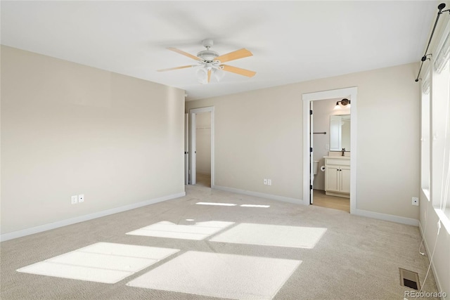 bedroom featuring ceiling fan, light colored carpet, and ensuite bath