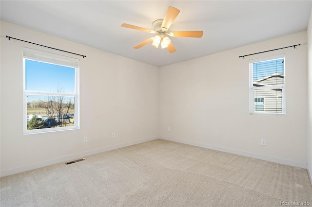 empty room featuring light carpet, visible vents, ceiling fan, and baseboards