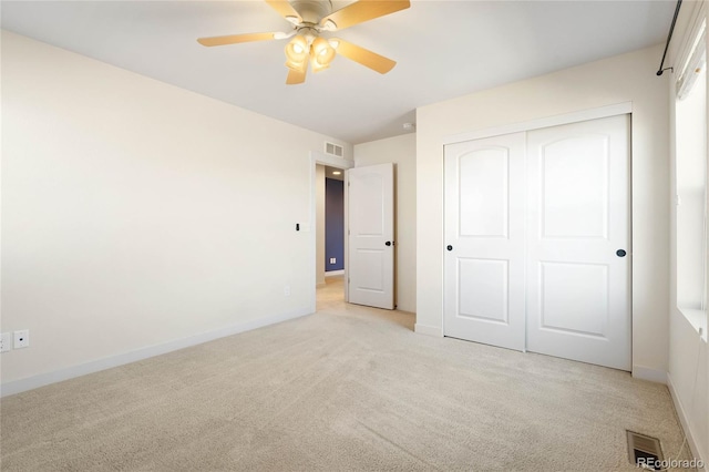 unfurnished bedroom with visible vents, baseboards, light colored carpet, a closet, and a ceiling fan